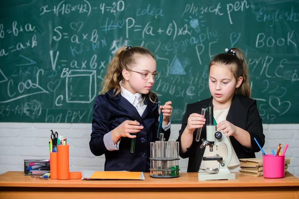 Girls classmates study chemistry. Microscope and test tubes on table. Perform chemical reactions. Basic knowledge of chemistry. Make studying chemistry interesting. Educational experiment concept — Stock Photo, Image