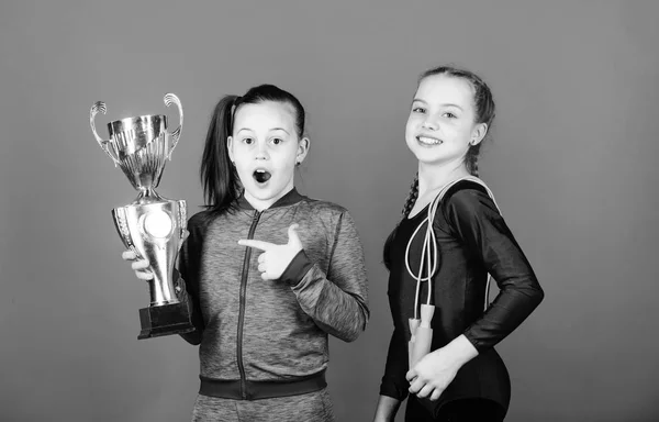 Happy children with gold champion cup. Acrobatics and gymnastics. Little girls hold jump rope. victory of teen girls. Winners in competition. Sport success. Little champion. New champion