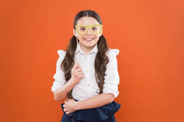 Een schoolmeisje in uniform. Een kind met een feestbril. slim en intelligent kind op oranje achtergrond. terug naar school. Grappig onderzoek. kennisdag. Gelukkige jeugd. Een kleine studente. Inspiratie — Stockfoto
