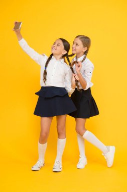Gülümse. Dijital teknoloji. Online eğitim. Bilgi günü. Akıllı telefonlu mutlu arkadaşlar. Çocuklar selfie çekerler, arkadaşlık yaparlar. Okul üniformalı küçük kızlar. Okula dönüyorum. eğitim günlüğü