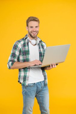 Hipster neşeli sakallı surat dizüstü bilgisayar tutuyor. Laptop tamircisi ya da teknoloji işçisi. İş ve eğlence için not defteri. Adam modern teknolojilerden hoşlanıyor. Kablosuz kulaklıklı dizüstü bilgisayar kullan