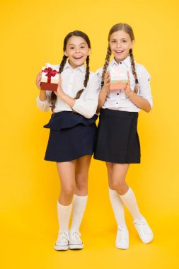 Büyük alışveriş günü. Mutlu kızlar sarı arka planda satışta hediyeler alıyor. Renkli kağıtlarla gülümseyen çocuklar okul üniforması giymiş kutular sunar. Tatil alışverişi konsepti