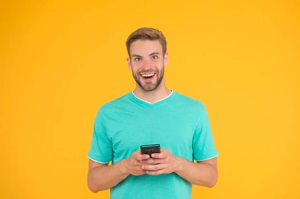 Descarga la aplicación. Guy jugar juego en el teléfono inteligente. Chico sonriente cara juego smartphone. Hombre probar aplicación para el teléfono inteligente. El hombre se aprovecha de la comunicación en línea. Aplicación móvil — Foto de Stock