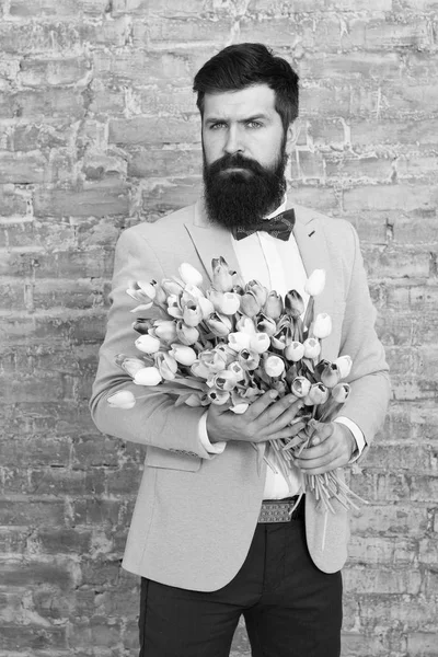 Invite her dating. Romantic man with flowers. Romantic gift. Macho getting ready romantic date. Waiting for darling. Tulips for sweetheart. Man well groomed wear tuxedo bow tie hold flowers bouquet — Stock Photo, Image