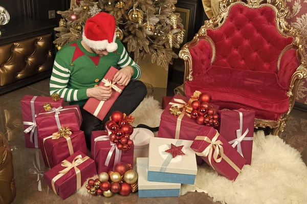 Disfrutando de la Navidad. El hombre con sombrero de santa celebrar regalos de Navidad. El tipo está celebrando la Navidad en casa. Entrega regalos de Navidad. Hombre feliz con cajas de regalo de Navidad. Adéntrate en el espíritu de la temporada — Foto de Stock