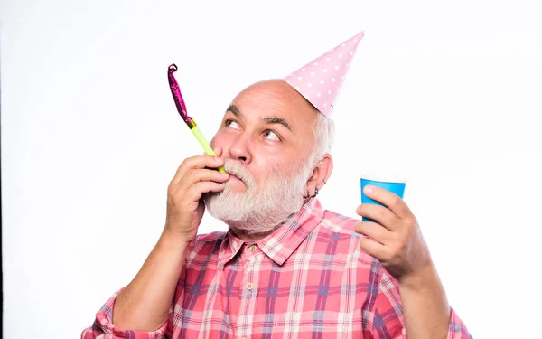 Birthday crazy party. Ideas seniors birthday celebrations. Elderly people. Man bearded grandpa with birthday cap and drink cup. Grandfather graybeard blowing party whistle. Getting older is still fun