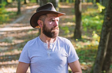 Kovboy modası. Kovboy şapkalı sakallı adam parkta açık havada yürüyor. sonbahar ormanında adam hipster. Bahar güneşli hava. kamp ve yürüyüş. acımasız bir görünüm ile olgun erkek. ciddi bir görünüm ile sakallı adam