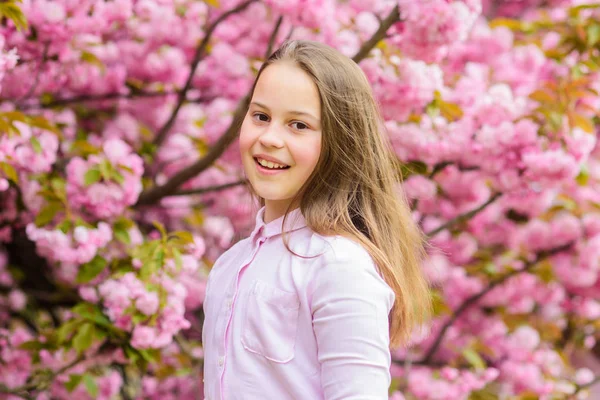 Little girl enjoy spring. Kid on pink flowers of sakura tree background. Kid enjoying cherry blossom sakura. Happy spring vacation. Spring in botany garden. That is how spring smells. Tender bloom — Stock Photo, Image