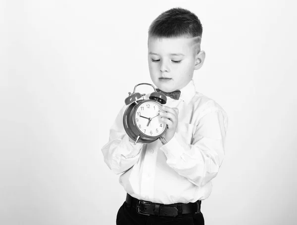 Preparar despertador. Criança menino segurar relógio vermelho. Está na hora. Programação e timing. De manhã. Escolar com despertador. Miúdo adorável menino branco camisa laço vermelho. Desenvolver auto-disciplina — Fotografia de Stock