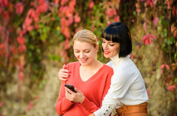 Compre online. Tecnologia moderna. A navegar na Internet. A comunicar online. Meninas comunicando olhando para o telefone. Conceito de redes sociais. Duas mulheres com smartphone comunicando ao ar livre. Ligação de partilha — Fotografia de Stock