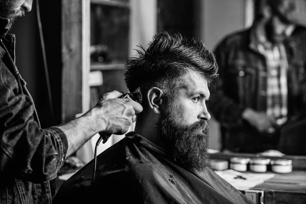 Styling saç kesme makinesi ile acımasız sakallı istemcisinin berber. Kuaför saç kesme makinesi ile saç modeli sakallı adam berber arka plan için çalışır. Hipster yaşam tarzı kavramı. Hipster istemci Başlarken saç kesimi — Stok fotoğraf