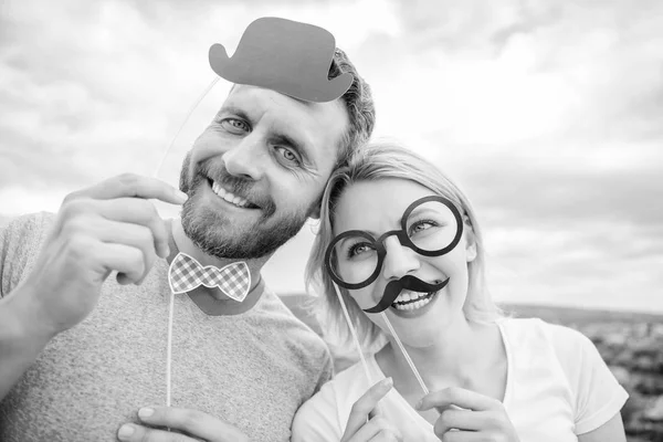 Photo booth props. Man with beard and woman having fun party. Add some fun. Making funny photos birthday party. Just for fun. Humor and laugh concept. Couple posing with party props sky background