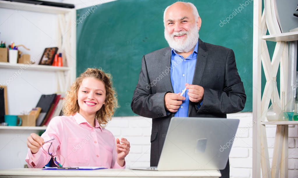 Having fun together. student and tutor with laptop. happy student girl with tutor man at blackboard. pass exam. teachers room. senior teacher and woman at school lesson. modern school education