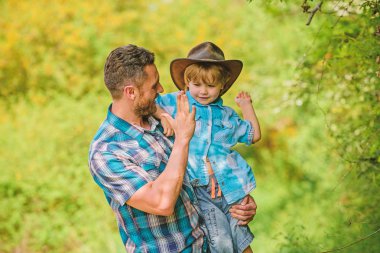 Ormanda mutlu bir baba. İnsan ve doğa. Aile günü. Dünya günün kutlu olsun. Eko çiftliği. Küçük çocuk çiftçilikte babasına yardım ediyor. Baba oğul çiftlikte kovboy şapkası takıyor. Lastik çizmeli çocuk. Çiftlik kovboyu