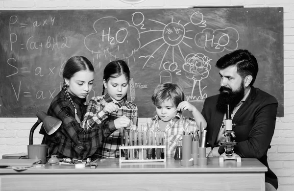 making experiment in lab or chemical cabinet. back to school. chemistry lab. happy children teacher. kids in lab coat learning chemistry in school laboratory. Young and confident scientist