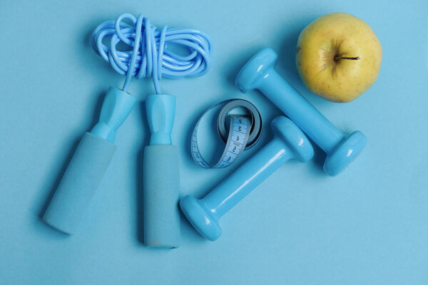Apple, tape, dumbbells and skipping rope in cyan color