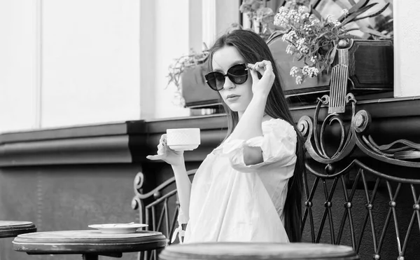 Breakfast time in cafe. Girl enjoy morning coffee. Waiting for date. Woman in sunglasses drink coffee outdoors. Girl relax in cafe cappuccino cup. Caffeine dose. Coffee for energetic successful day