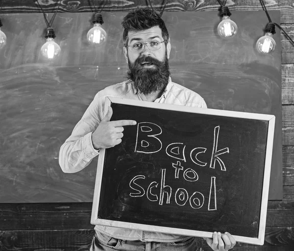 Nauczyciel w okularach posiada tablica z napisem: powrót do szkoły. Powrót do koncepcji szkoły. Człowiek z broda i wąsy na wesołą twarz z zadowoleniem przyjmuje studentów, tablica na tle — Zdjęcie stockowe