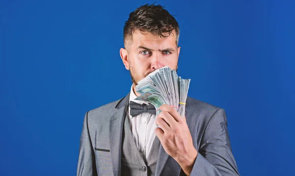 Easy cash loans. Man formal suit hold pile of dollar banknotes blue background. Businessman got cash money. Richness and wellbeing concept. Get cash money easy and quickly. Smell of money