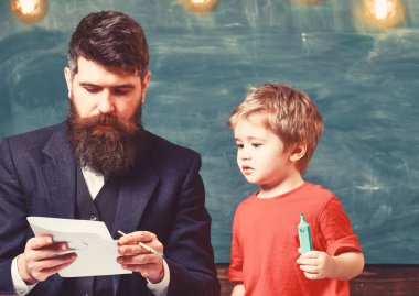 Çocuk ve meşgul yüz boyama, resim öğretmeni. Sakallı öğretmeni, sınıfta, kara tahta arka plan çizmek için küçük oğlu baba öğretir. Sanat ders kavramı. Yetenekli sanatçı oğlumla vakit geçirmek