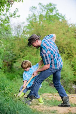 Toprağı zenginleştirmek. mutlu dünya günü. Kürekli mağara kaz. baba ve oğul aile ağacı dikiyor. yeni bir hayat. toprak gübreleri. zengin doğal toprak. Eko çiftlik. Çiftliği. küçük çocuk çocuk tarım baba yardım
