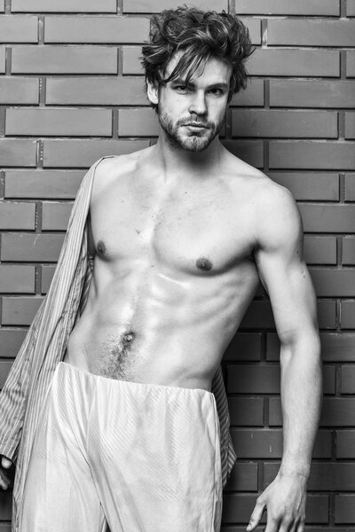 Мужчина спортсмен с подходящим туловищем. Парень с блестящей кожей раздевает халат. Спортсмен показывает сексуальный торс. Сексуальная грудь и живот холостяка. Сексуально привлекательный мачо взъерошенные волосы на деревянном фоне
