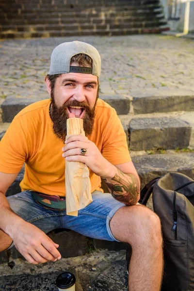 Comida de plástico. Um tipo a comer cachorros quentes. Homem barbudo desfrutar de lanche rápido. Comida de rua tão boa. Estilo de vida urbano e nutrição pouco saudável. Despreocupado hipster comer junk food while sit on stairs. Lanche de homem faminto — Fotografia de Stock