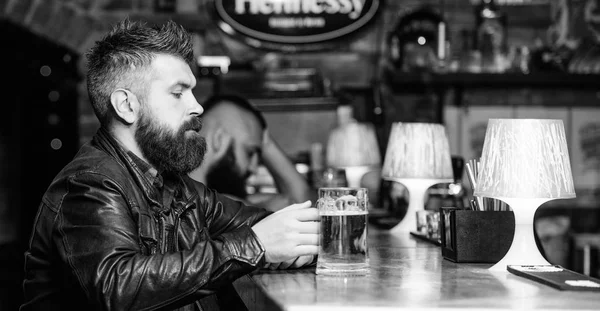 Hipster ontspannen bij pub. Guy bebaarde man zitten op toog in pub. Man met baard doorbrengen vrijetijdsbesteding in donkere pub. Brutale hipster ontspannen. Weekend levensstijl. Pub geweldige plek om te dineren drankje en veel plezier — Stockfoto