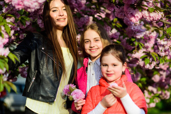 happy sisters in cherry flower. Sakura bloom. Natural beauty. Mothers day. family summer. small children and mother in spring flower. blossom smell, allergy. Sisterhood. In great mood