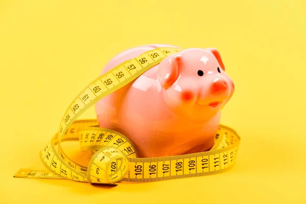 belt tightening. Economy and budget increase. piggy bank with measurement tape. Moneybox. loan concept. Take credit. low pay. Saving money. Deposit. money diet. finance and commerce