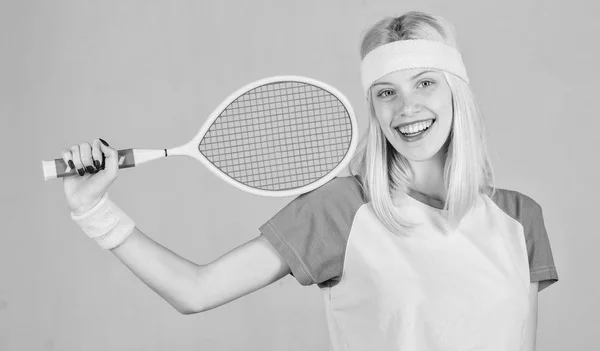 Gadis pirang menggemaskan bermain tenis. Olahraga untuk menjaga kesehatan. Kesenangan dan hobi yang aktif. Atlet memegang raket tenis di tangan dengan latar belakang abu-abu. Olahraga tenis dan hiburan. Konsep klub tenis — Stok Foto