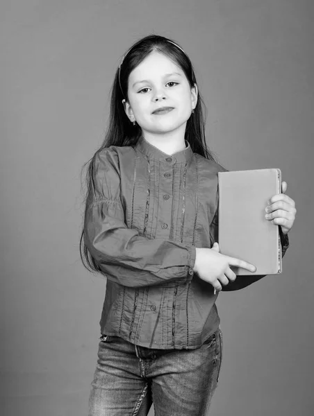 Confiante en ses connaissances. Adorable petit livre de tenue de fille avec couverture orange. Petit enfant mignon avec la connaissance du livre dans les mains. Connaissances et compétences. Journée du savoir ou 1er septembre, espace de copie — Photo