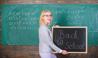 Yine okul zamanı. Okul öğretmeni öğrencileri ağırlamadan memnun. Okul yılının harika bir başlangıcı. Öğrencileri okula geri kabul etmenin en iyi yolları. Öğretmen kadın okula geri tahta yazıt tutun