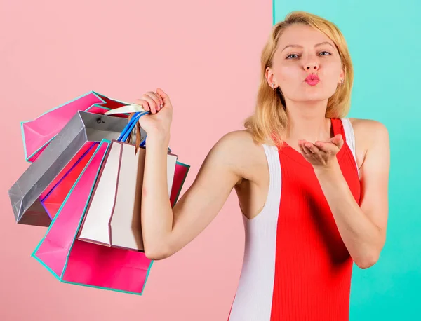 Κορίτσι ικανοποιημένος με τα ψώνια. Συμβουλές για την επιτυχή πώληση πωλήσεων. Κορίτσι απολαμβάνουν τα ψώνια ή μόλις πήρε δώρα γενεθλίων. Γυναίκα κόκκινο φόρεμα κρατήσει μάτσο τσάντες για ψώνια μπλε ροζ φόντο. Αγοράστε ό,τι θέλετε — Φωτογραφία Αρχείου