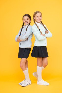 Okuldan beri birlikte. Eğitim. Okula geri dön. çocuk modası. Dostluk ve kardeşlik. Okul üniformalı mutlu kızlar. sarı arka planda akıllı küçük kızlar. bilgi günü. çocukluk mutluluğu
