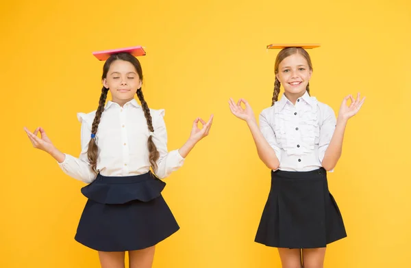 Iskoláslányok barátai együtt tanulnak. A gyerekek egyenruhája könyvet tart. Életegyensúly. Elviselem az iskolai stresszt. Gyakorold a meditációt. Egyensúlyt. Harmónia koncepció. Béke és egyensúly. Reméljük a legjobbakat. — Stock Fotó