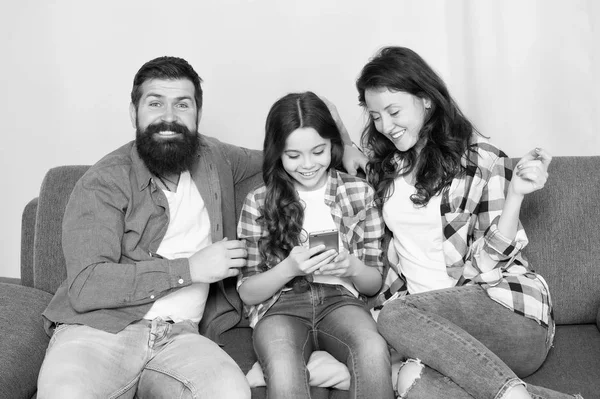 Conselheiro dos pais. A família passa o fim de semana juntos. Criança menina usar smartphone com os pais. Família amigável se divertindo juntos. Mãe pai e filha ocupada relaxando no sofá. Lazer familiar — Fotografia de Stock