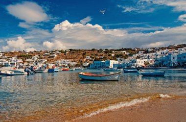 Mykonos, Yunanistan - 04 Mayıs 2010: deniz beach, tekneler. Deniz kıyısında bulutlu mavi gökyüzü. Akdeniz köy evler dağ manzarası ile. Adada tatil yaz. Yolculuk tutkusu ve seyahat