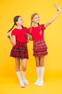 Komik arkadaşlar. Eğleniyorum. Kardeşlik ve dostluk. Bilgi günün kutlu olsun. çocukluk mutluluğu. Eğitim konsepti. Okula dönüyorum. Sosyal ağ. Üniformalı kızlar. Küçük kızlar telefonda selfie çekiyor.