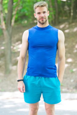 Sağlıklı ve kaslı. Yaz gününde kaslı adam eğitimi. Kaslı kolları olan atletik adam parkta çaprazlanmış. Yakışıklı sporcu veya kas gücü ve gücü ile atlet