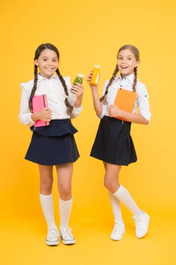 Susuzluk ve susuzluk. Sağlıklı snack meyve yüzlü. Smoothie detoksu. Nefis smoothie. Sağlıklı beslenme. Kız öğrenciler sarı arka planda meyve suyu şişesi tutuyorlar. Okul sırasında susuzluğu giderme