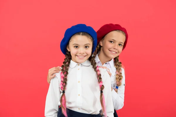 Schulfreunde. glückliche kleine Freundinnen auf rosa Hintergrund. liebenswerte Freunde, die Freundschaft genießen. Kleine Schulfreunde lächeln in Uniform und stylischen Baskenmützen — Stockfoto