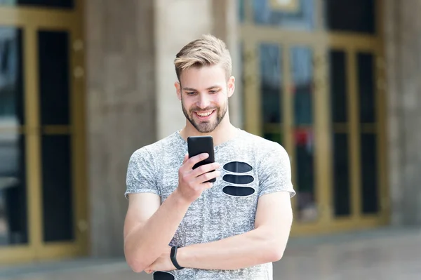 Phone created for those who live on edge. Happy man talking on mobile phone on urban outdoor. Caucasian hipster using loudspeaker mode in his phone. Making a call with portable telephone or phone