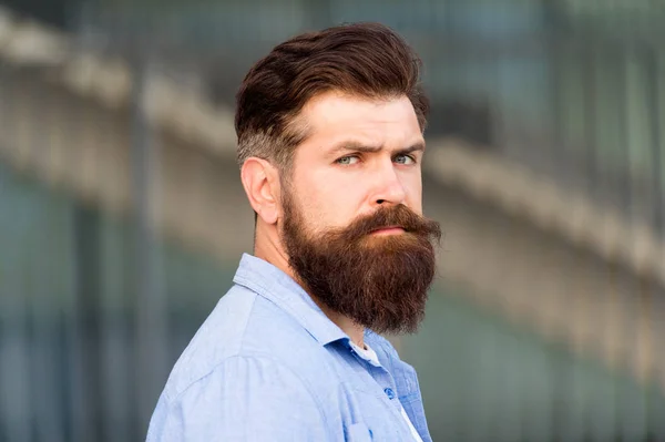 Peluquería y peluquería. Belleza masculina. Consejos para peinar el cabello. Crea estilo personal con vello facial. Hipster con barba elegante y bigote de fondo urbano. Barbudo hombre sin afeitar pelo de la cara — Foto de Stock