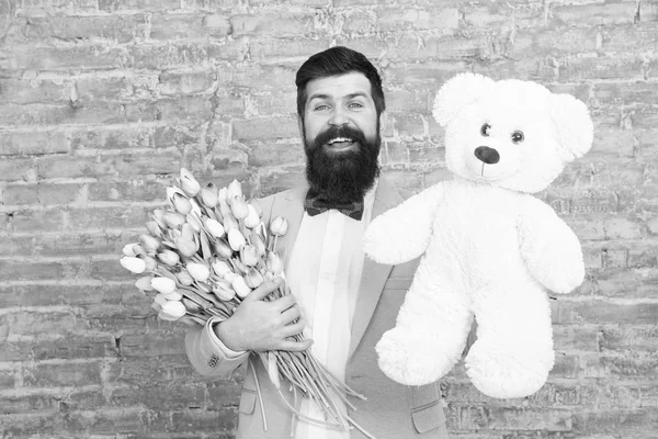 Bonne journée de printemps. homme amoureux. Cadeau de printemps. Homme barbu hipster avec des fleurs. Homme barbu avec bouquet de tulipes, ours. Un rendez-vous amoureux. vacances internationales. Fleur pour le 8 mars. Journée des femmes. Heureux homme barbu — Photo