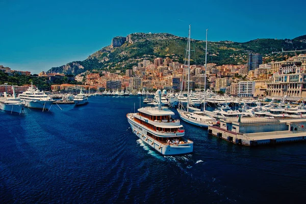 Monte Carlo, Mônaco - 08 de dezembro de 2009: navio entra no porto marítimo com casas em paisagem montanhosa. Clube de iate e cidade à beira-mar de verão. Aventura marítima e passeios de barco. Férias e desejo de viajar — Fotografia de Stock