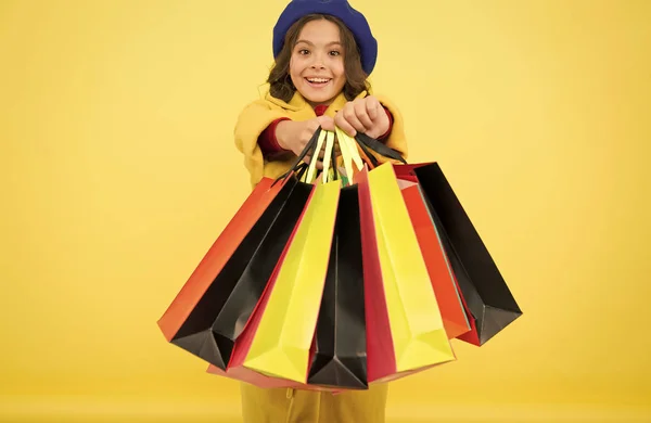 Fashionista adoro ir de compras. Obsesionado con las compras. Niña lindo niño mantenga bolsas de compras sobre fondo amarillo. Venta a mitad de temporada. Tienda con tarjeta de descuento. Obtener descuento de compras en cumpleaños o vacaciones —  Fotos de Stock