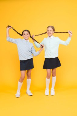 Sakinleşme zamanı. Okul üniformalı mutlu kızlar. Sarı arka plandaki akıllı küçük kızlar. Çocuk modası. Arkadaşlık ve kardeşlik. Bilgi günü. çocukluk mutluluğu. Eğitim konsepti. Okula geri dön.