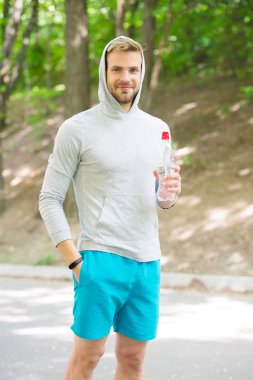 Susuz kalma. Sporcu parktaki eğitimden sonra su içer. Sporcu kıyafetleri su dengesini önemser. Sağlıklı bir yaşam tarzı. Vitamin ve mineraller. Sporcu adam elinde şişe suyu tutuyor.