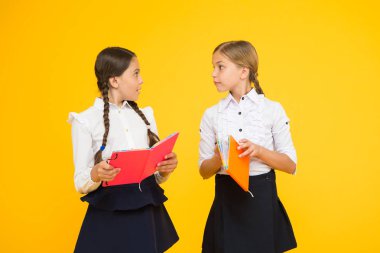 Dil eğitimi. Sevimli çocuklar ders kitabı ile çalışır. Okul çalışmaları için okuma becerilerini pratik edin ve geliştirin. Okul konseptine geri dönelim. Kızlar kitap tutar. Kız öğrenciler sarı arka plan üzerinde birlikte çalışma